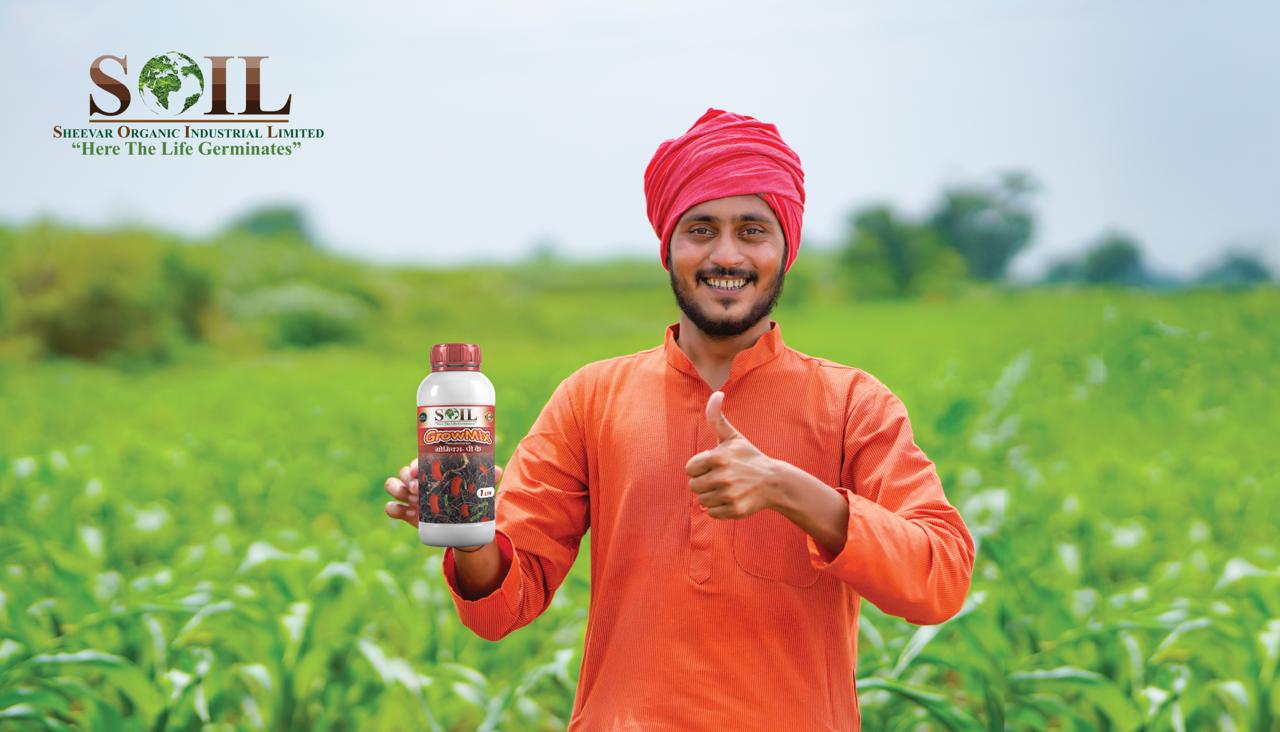 Farmer holding SOIL product in green field